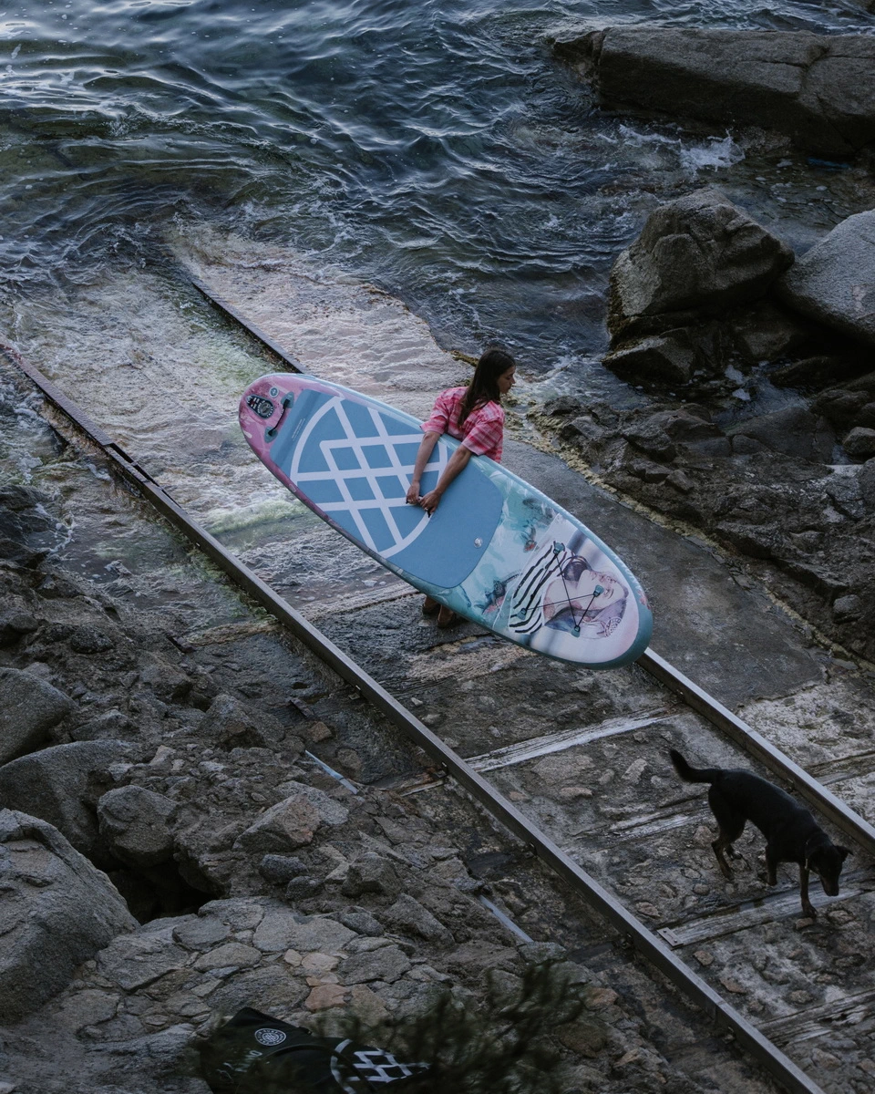 chica en la orilla de las rocas del mar con una tabla de sup surf